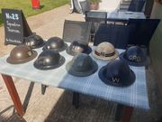 Nine British wartime helmets, mostly Civil Defence, laid out on a table outside the No. 25 Squadron Tearoom