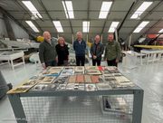 Photographs and documents of S/Ldr Victor Ekins laid out on a table at the Museum, with the donors and Museum representatives behind
