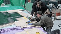 Dave holds the wing marking stencil as Julian sprays.